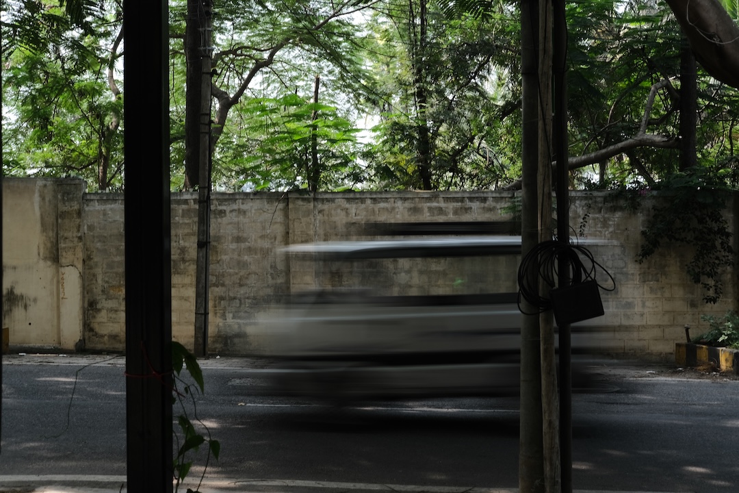 A van driving down the inclined street lined with trees